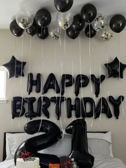 A sleek and simple 21st birthday room decoration. Black balloons, "Happy Birthday" foil letters, and large number foils create a cool and modern vibe.