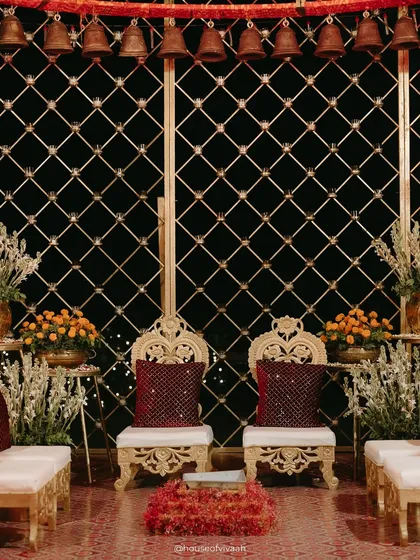 The bride and groom's ornate seating inside the bell mandap, framed by a golden lattice and hanging temple bells, creating an intimate and sacred space for the couple.