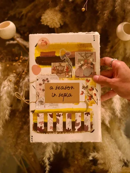 Our cocktail menus are more than just a list of drinks; they are handmade scrapbooks, each telling a unique story. This is the cover of 'A Season in Sepia,' our autumn menu, reflecting our commitment to artistry and a narrative-driven beverage program.