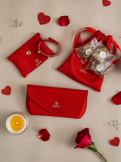 Valentine's is here and so are we. A festive flat-lay for a Valentine's Day jewelry gift set, using red pouches, rose petals, and heart-shaped glitter to create a romantic theme.