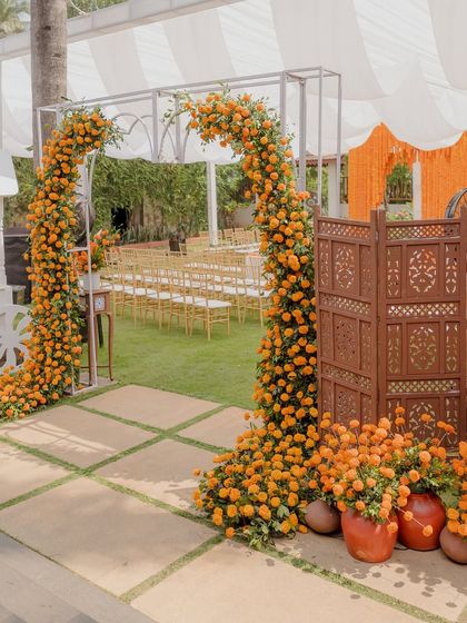 The entrance to the Haldi ceremony, featuring a simple arch adorned with marigolds and flanked by rustic wooden screens.