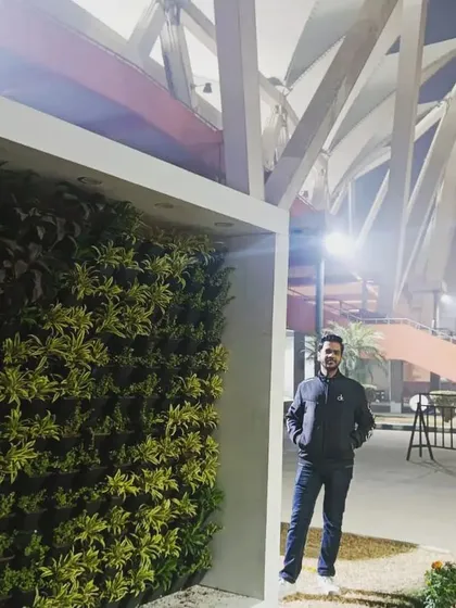 The completed vertical garden at Nehru Stadium, viewed at night. The structure stands as a beautiful green monument against the stadium's iconic architecture.