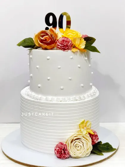 A classic and clean two-tier cake for a 90th birthday. The simple line texture and polka dots are complemented by beautiful, handmade sugar flowers.