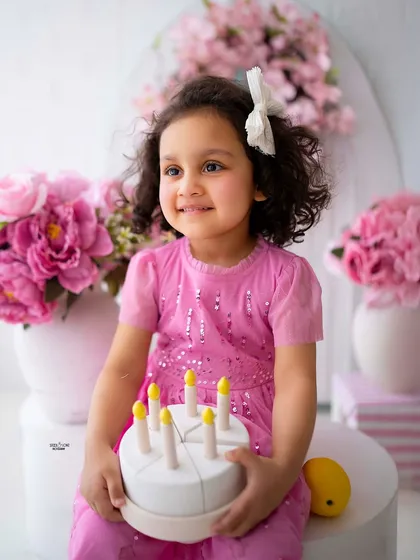 Holding her birthday cake with a gentle smile. A classic portrait from her milestone session.