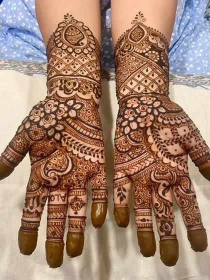 A dense and intricate design where paisleys and florals are woven together, covering the hands completely for a very traditional feel.