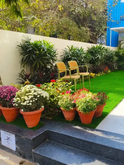 Another view of the charming garden seating area, highlighting the mix of potted seasonal flowers and permanent shrubs.