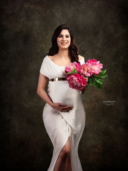 A sweet and gentle portrait of a mom-to-be in a white off-shoulder gown, holding a bouquet of pink peonies. The classic dark backdrop highlights her radiant glow.