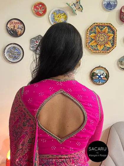 The back view of the pink bandini blouse, showing the teardrop-shaped cutout framed with delicate beadwork.
