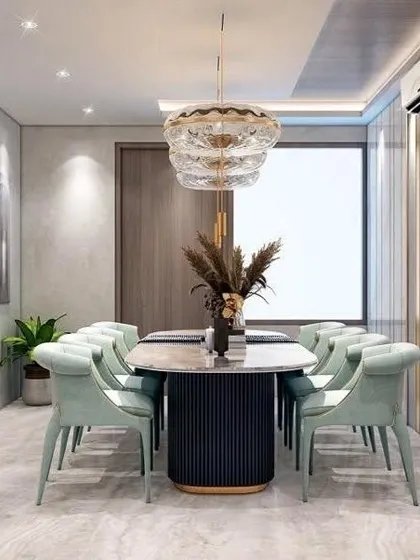 The dining area continues the theme of modern luxury with mint green chairs and a statement chandelier. The clean lines and sophisticated materials create an elegant space for meals.