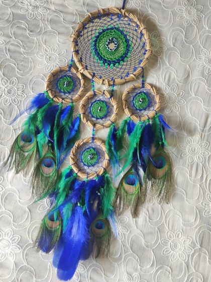 Capturing dreams with peacock elegance. This unique cluster dreamcatcher features real peacock feathers and small mirrors, reflecting the beauty and grace of India's national bird.