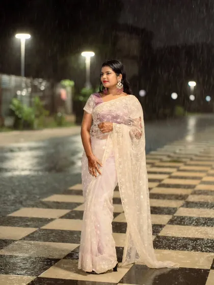A beautiful portrait of a woman in a saree during a downpour. The rain adds a dramatic and romantic element to this night shoot.