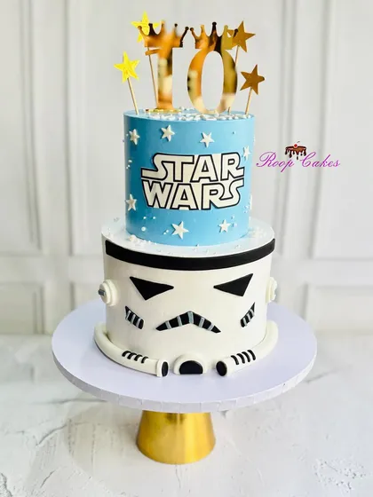 A galactic birthday celebration. This two-tier Star Wars themed cake features a Stormtrooper helmet base and a starry blue top tier with the iconic logo.
