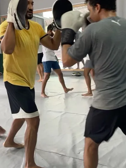 Close up on a partner drill, with one member holding pads while the other throws a punch.