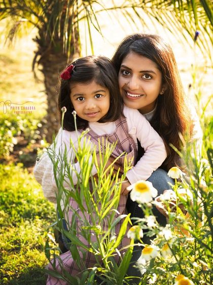 A mother and daughter share a beautiful moment among the flowers. The natural greenery and soft light make this outdoor portrait feel intimate and special.