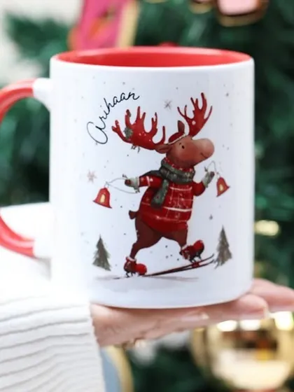 A whimsical Christmas mug with a reindeer on skates, personalised for 'Arihaan'.