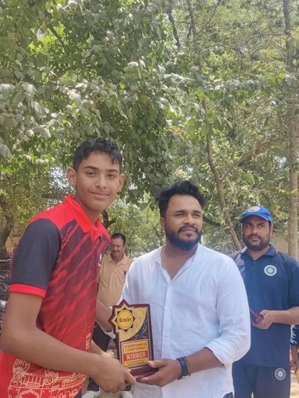 A young cricketer from the academy being recognized for his performance in a local tournament.