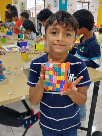 This young man is proud to show off the cool mosaic pen stand he made. A great and useful piece of art!