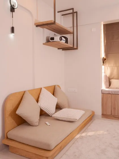This entertainment room at Mana Capitol features a low-seater sofa and unique ceiling-hung shelves, perfect for a projector setup in a minimalist style.