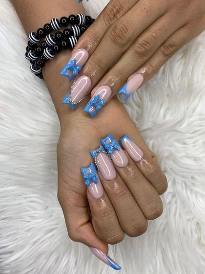 Bold blue 3D bows on a classic nude base. This design shows how a pop of color and texture can transform a simple manicure.