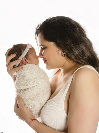 A mother's gentle gaze says it all. This simple, high-key portrait against a white background beautifully captures the intimate connection between a mother and her new baby.