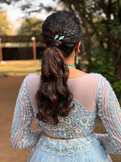 A stylish and modern ponytail with soft waves, perfect for a cocktail party or reception. The look is elevated with sparkling hairpins.