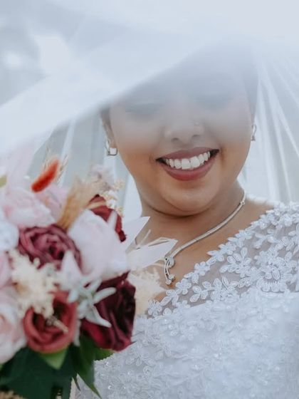 A bright and airy portrait of the bride, with her smile lighting up the frame. The focus is entirely on her happiness and the delicate details of her dress.