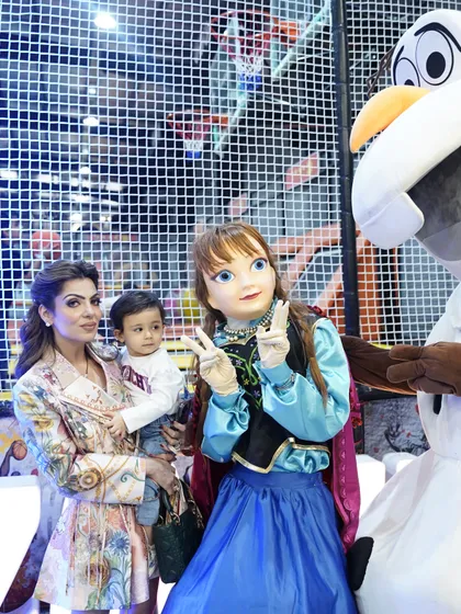 A mother and her baby pose with the Anna and Olaf mascots, a memorable moment for the whole family.