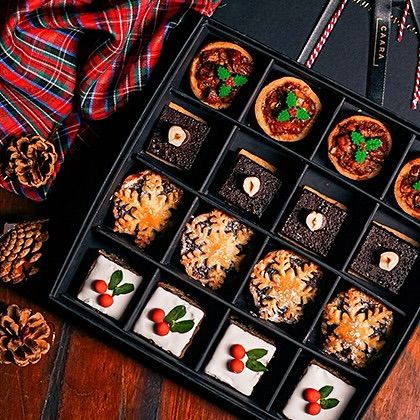 A closer look at our sixteen-piece Christmas sweet box. The assortment features intricate details like holly decorations on the mince pies and snowflake patterns on the fruitcake.