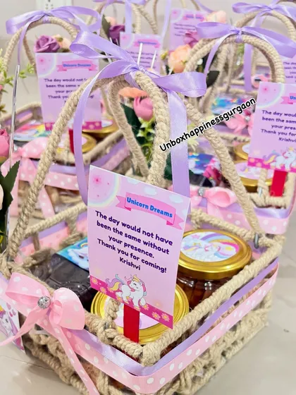 This image focuses on a single unicorn return gift basket, complete with a personalized thank you note and floral decorations.