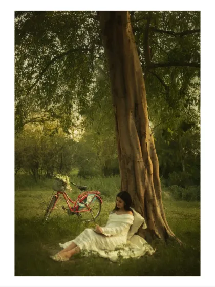 A poetic scene of a mother-to-be reading under a tree, with a vintage bicycle nearby. This styled shot creates a timeless, storybook feel, perfect for a dreamy maternity portrait.