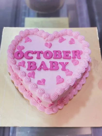 A heart-shaped pink bento cake for an "October Baby."