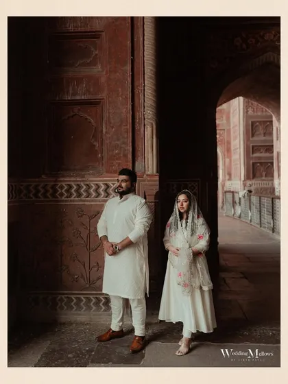 A regal portrait inside the beautiful archways of the Taj Mahal complex. The rich red stone and intricate architecture create a stunning frame for this elegant pre-wedding photo.