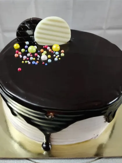 A chocolate drip cake decorated with chocolate buttons and colorful sprinkles. A fun and festive choice for any birthday.