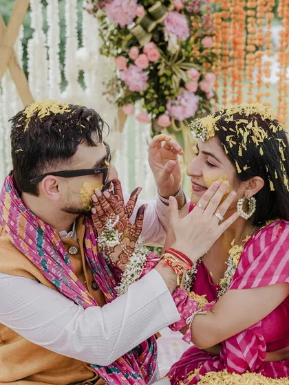 The Haldi ceremony is a burst of joy, and we capture every bit of that playful energy. This shot of the couple being showered with flowers shows our love for vibrant, candid moments that are full of life and laughter.