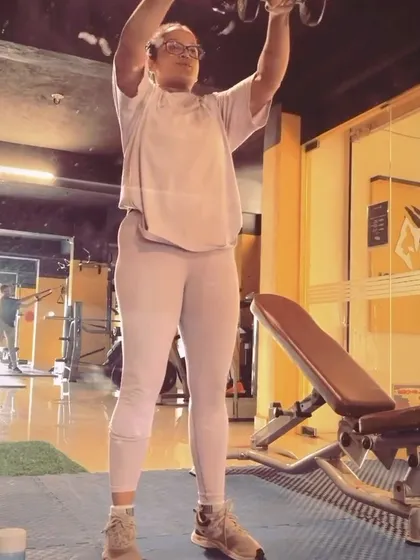 This image shows a client executing a dumbbell shoulder press. This is a fundamental movement for developing upper body strength and stability.