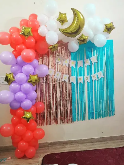 Another view of the naming ceremony backdrop, showing the half-arch of red, purple, and white balloons with a 'Happy Ceremony' banner.