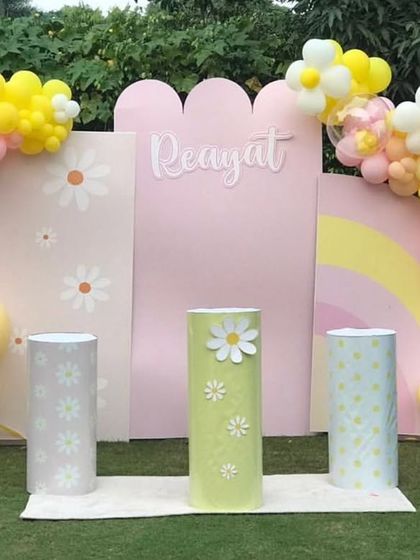A sweet daisy-themed party with modern, arched backdrops. The pastel yellow and pink balloon garlands are shaped into flowers, adding a charming touch.