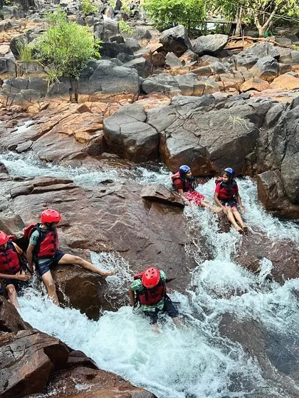 A wide view of students enjoying the rocky riverbed and natural water slides during their summer camp in Dandeli.