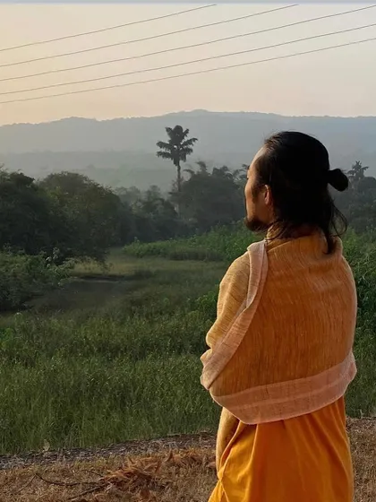 A student takes a moment for quiet contemplation, looking out over the lush green valley. Our ashram provides many such spaces for personal reflection.
