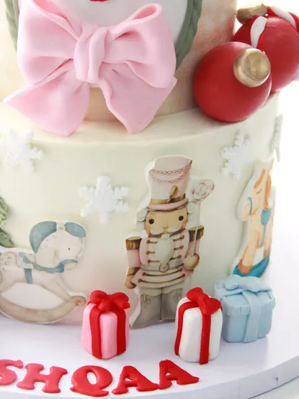 A detail shot of the hand-painted nutcracker and rocking horse on the side of the festive Christmas cake.