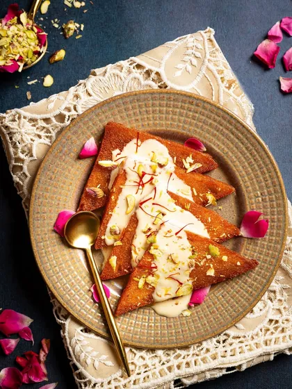 Traditional Shahi Tukda, a rich Indian dessert, styled with rose petals and pistachios to highlight its royal origins.