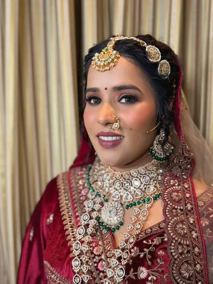 A close-up of the bride's regal look. The heavy kundan and emerald jewelry is the centerpiece, balanced by a sophisticated makeup look.