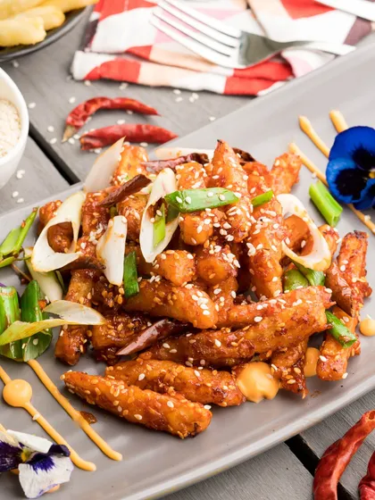 Crispy Honey Chilli Potato, perfectly fried and tossed in a sweet and spicy sauce, garnished with sesame seeds. An addictive vegetarian starter.