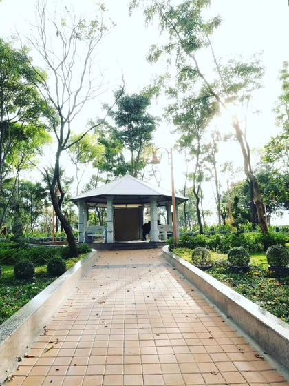 A view down a paved path leading to the park gazebo, framed by mature trees. This demonstrates how I design sightlines to draw people through a landscape.