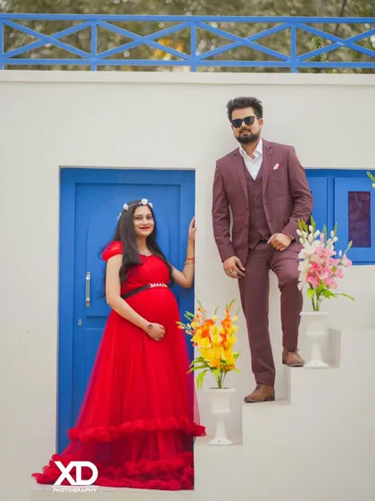A fashionable couple poses on a white staircase against a blue door, creating a chic, magazine-style photo.