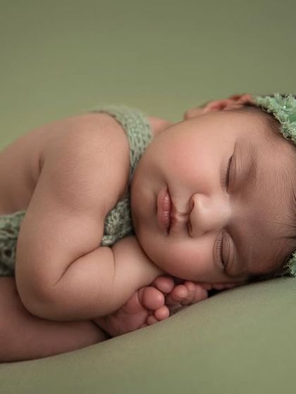 The 'taco' pose, showing the baby curled up and sleeping soundly. The matching green headband completes the look.