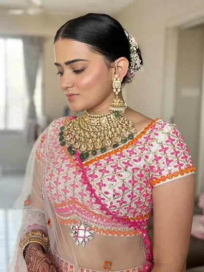 Radiant in blush, captivating in nude. This look features beautifully blushed cheeks, a soft nude lip, and a clean, elegant bun, perfect for a traditional ceremony.