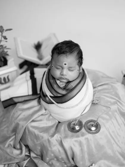 A close-up black and white shot of the baby in the Warkari setup, highlighting the traditional sandalwood paste markings (tilak).