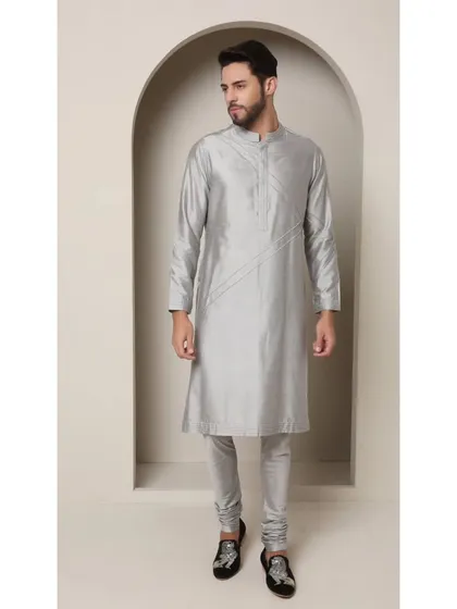 A simple yet elegant grey silk kurta with churidar. The beauty of this piece lies in its clean lines, subtle pintuck details, and the lustrous quality of the fabric.