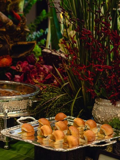 Bite-sized sliders, perfect for mingling, are presented on an elegant silver tray. We ensure that even casual food items are served with sophistication and style.